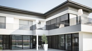 Modernes Haus mit großen Fenstern und Jalousien