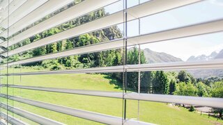 Blick durch offene Lamellen auf grüne Landschaft